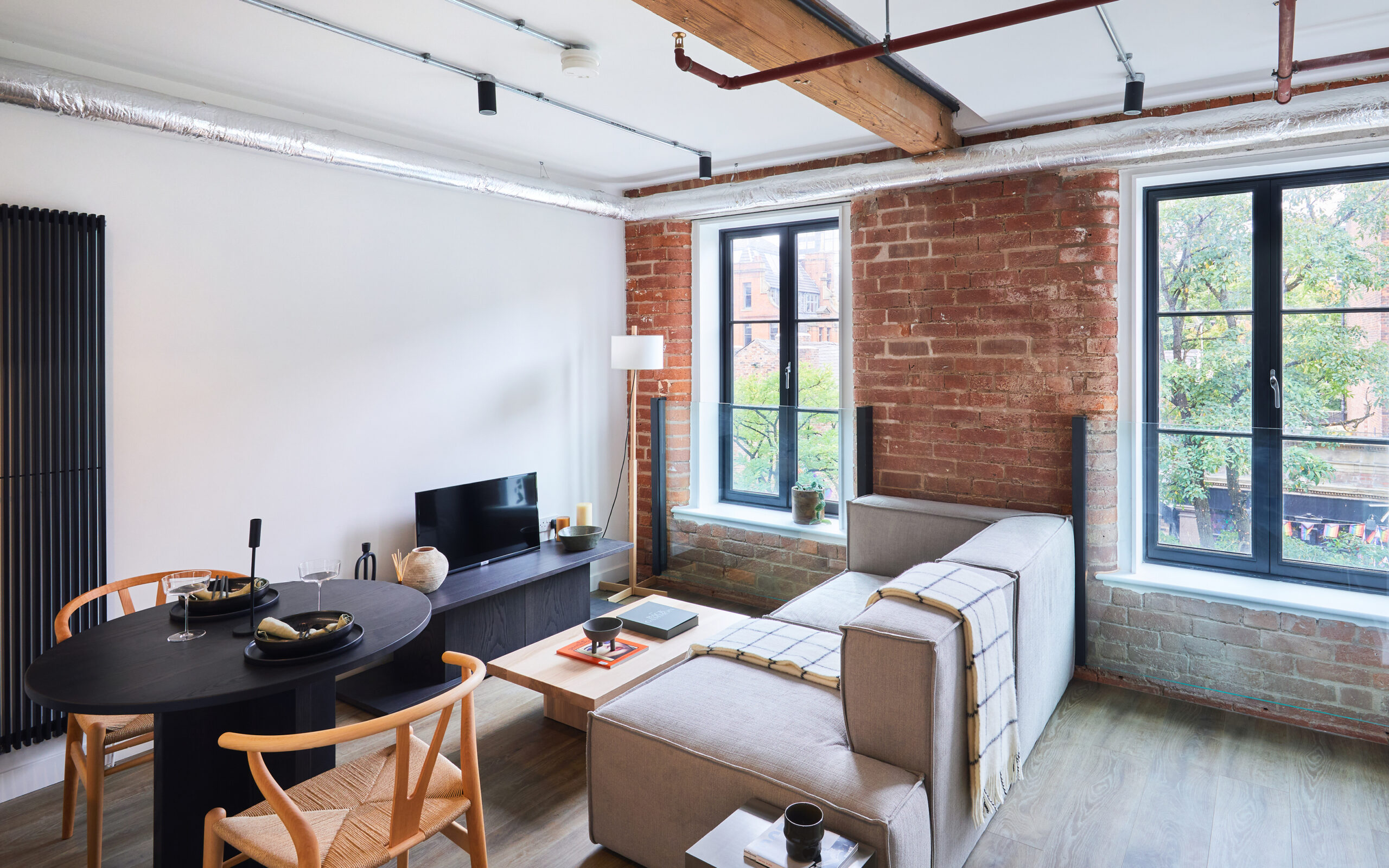 living space with wooden beams and industrial piping on ceiling.