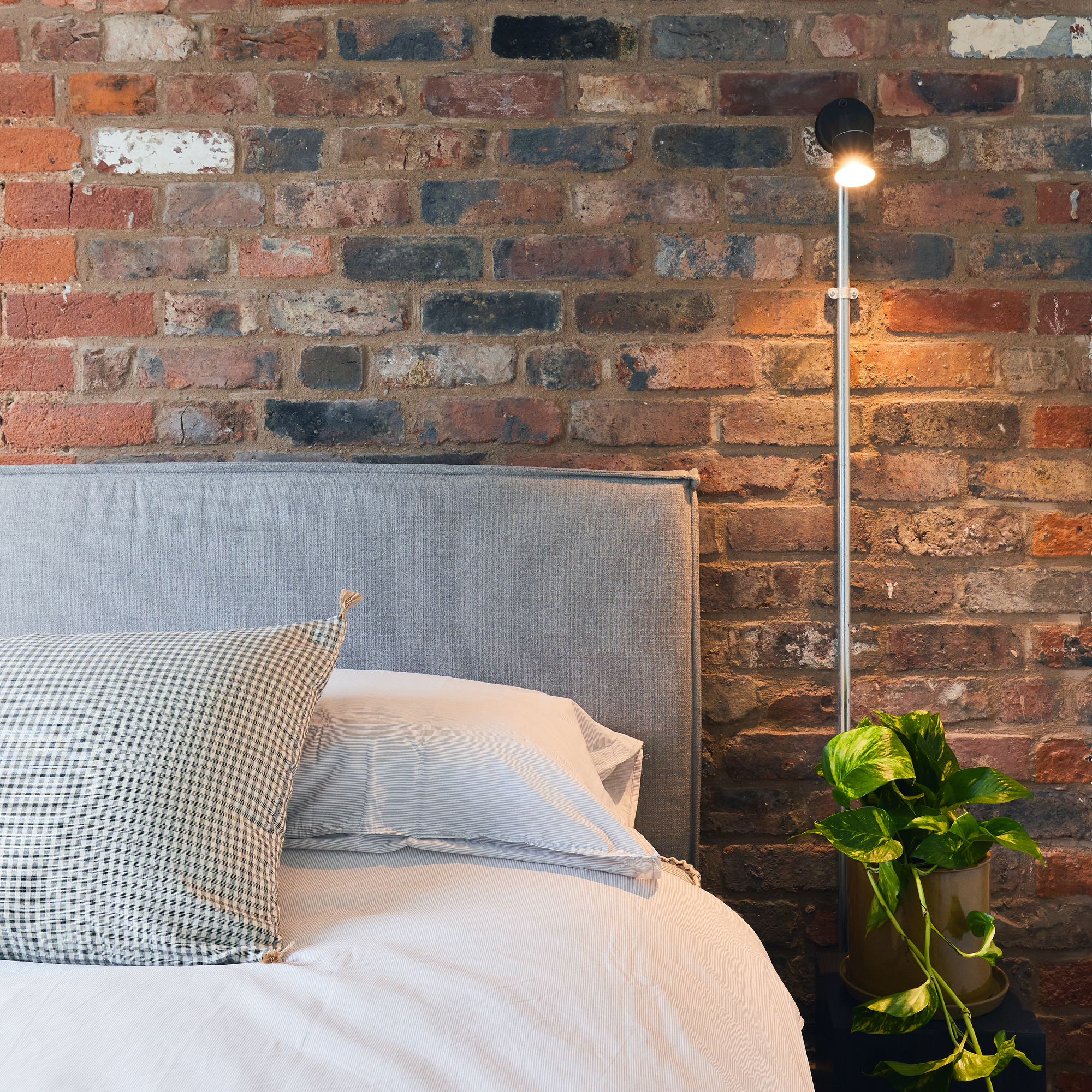 Modern sleeping space with raw brickwork and houseplants.