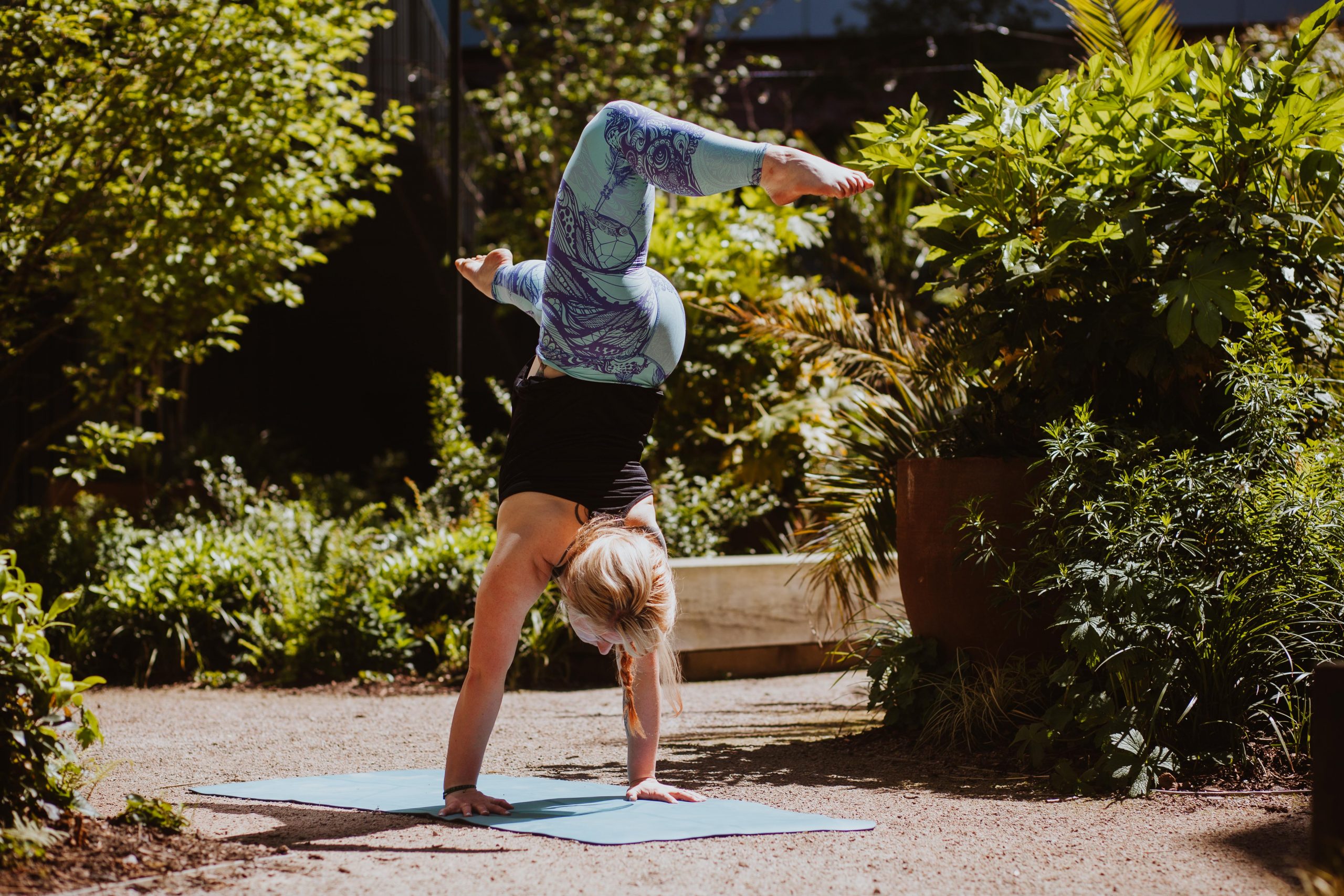 A woman perfoming a handstand yoga pose outside.